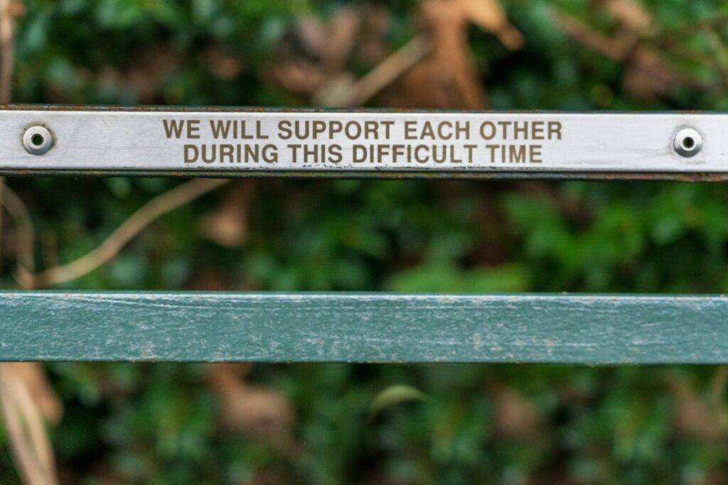 bench with top piece that says "we will support ecah other during this difficult time"