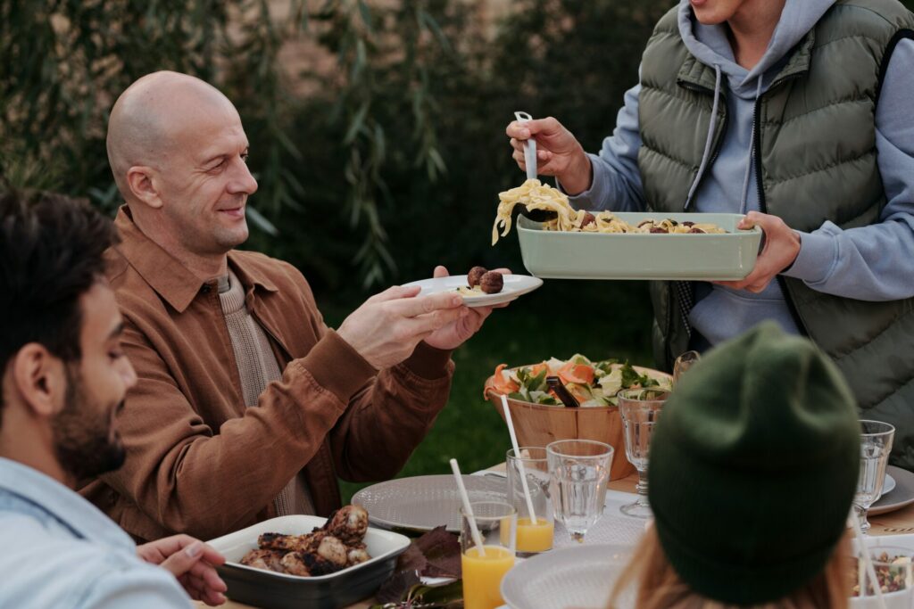 man sitting at table with other being served by a friend