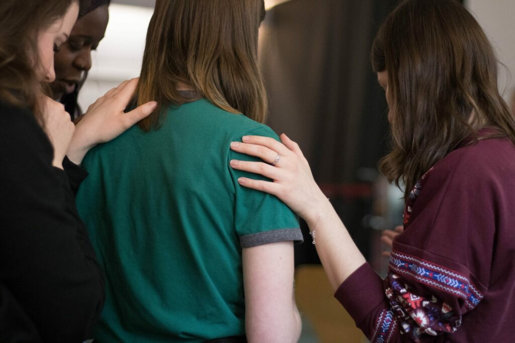 woman with others hands on her praying for her