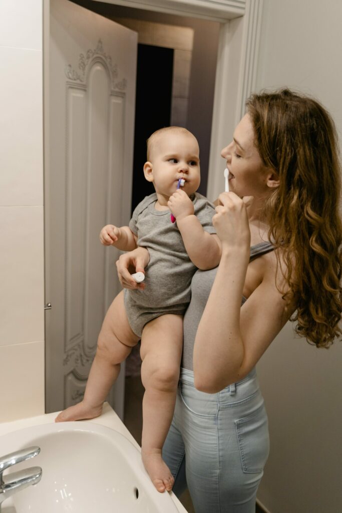 mom and baby brushing their teeth at a sink