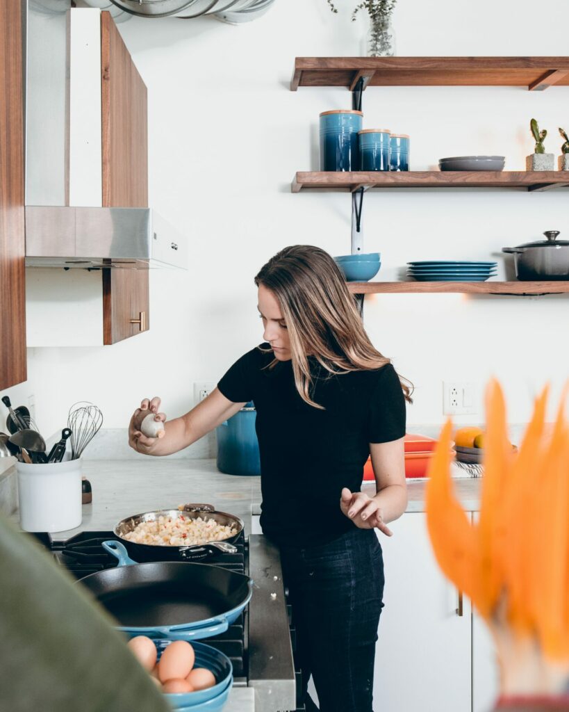 woman sprinkling spice into cooking pan