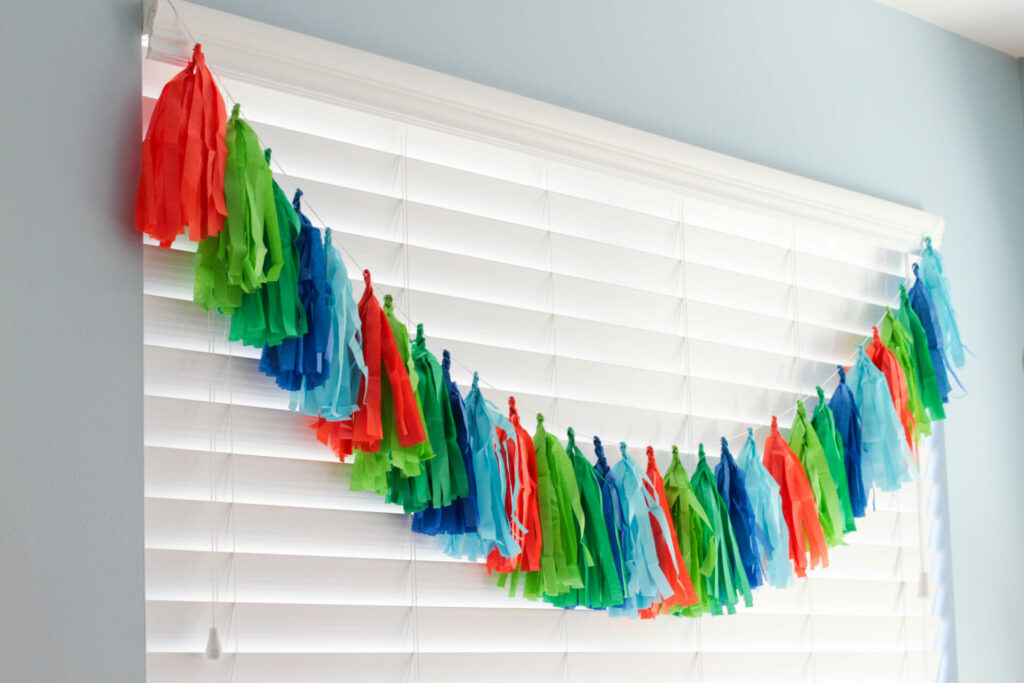 tassel garland across window in party colors for a dinosaur birthday party