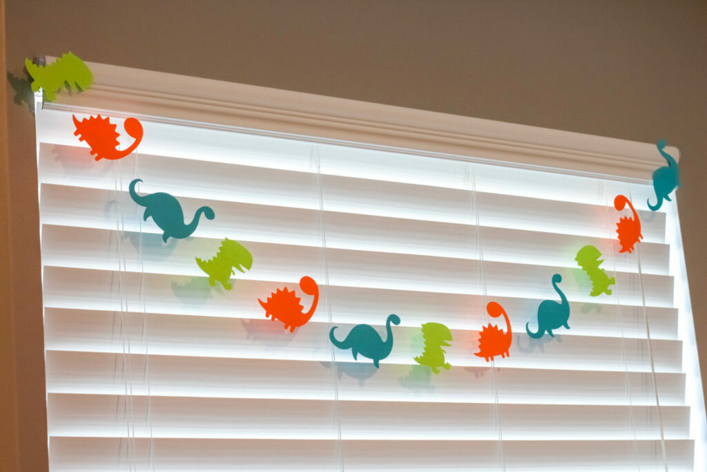 dinosaur garland across the top of a window for a dinosaur birthday party