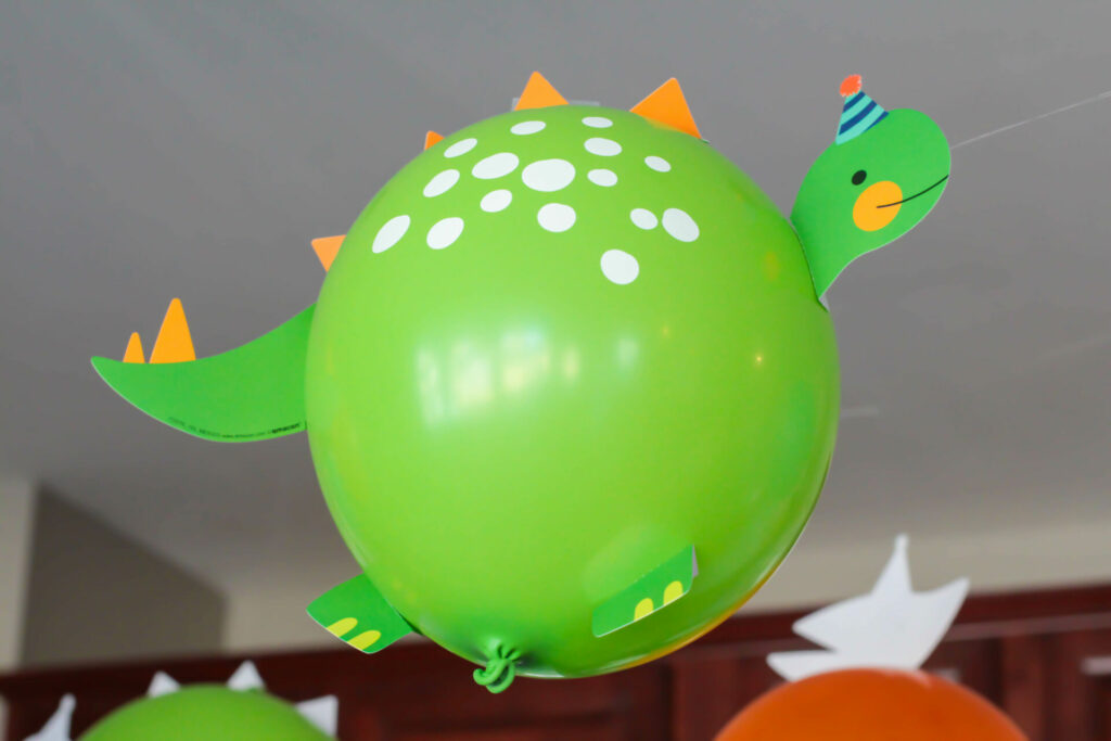 green balloon made to look like a dinosaur with taped on pieces