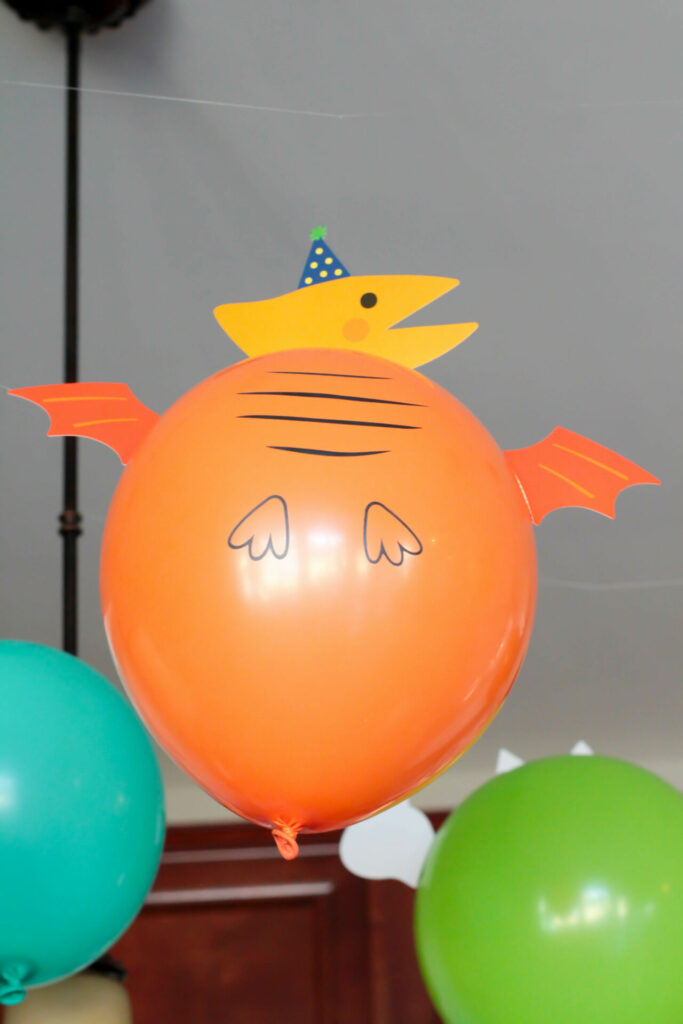 orange balloon made to look like a dinosaur with taped on pieces