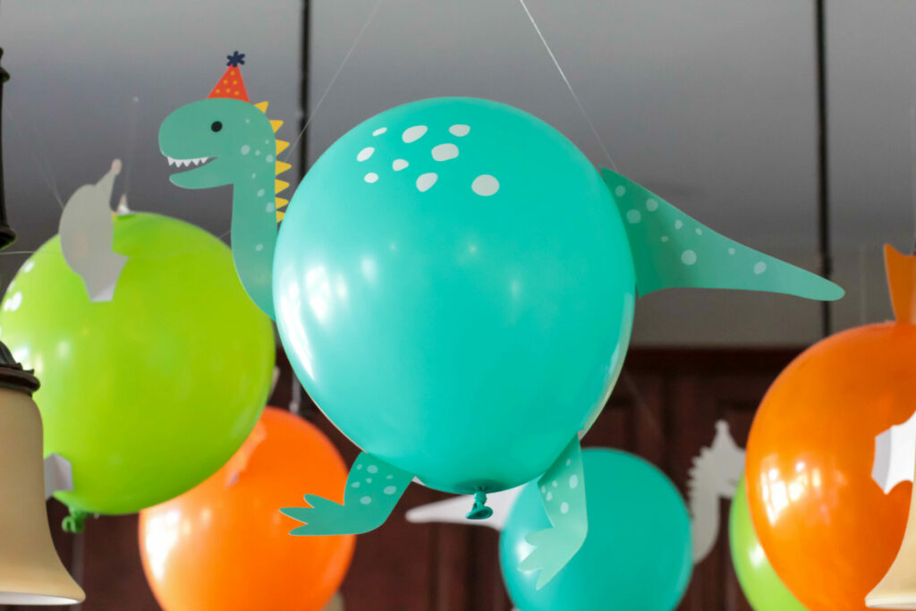 teal balloon made to look like a dinosaur with taped on pieces