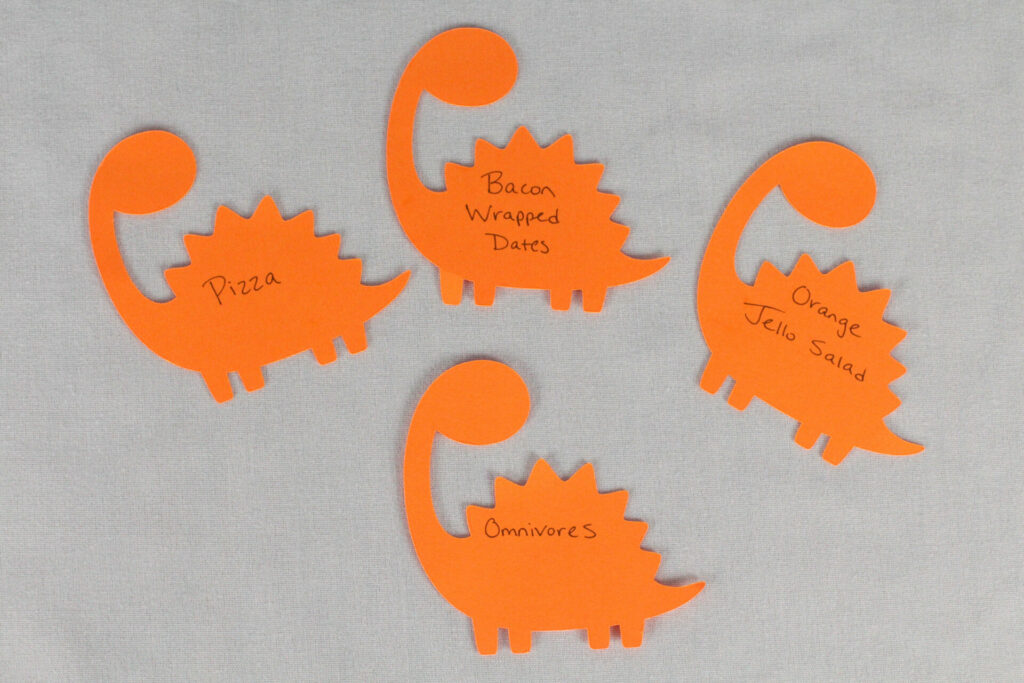 Omnivore food tags made from paper dinosaurs for dinosaur birthday party