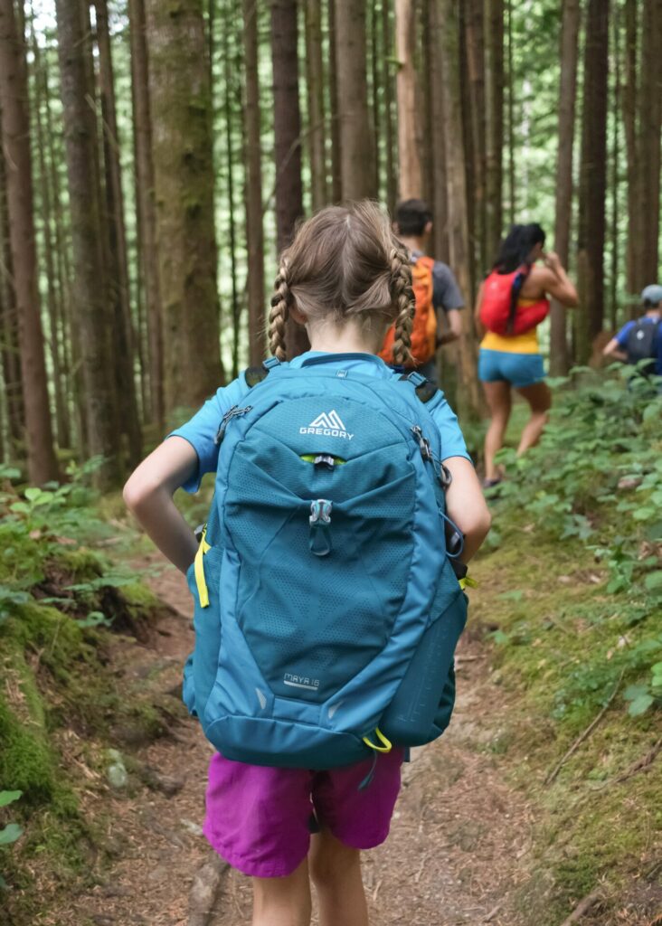 girl hiking through woods with her family