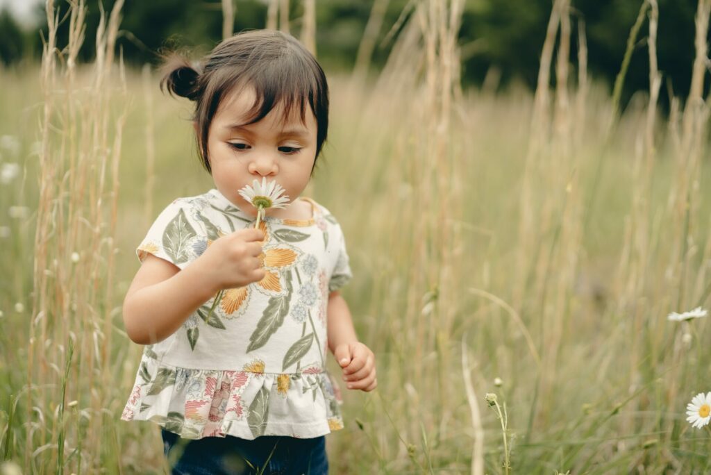 child smelling flower in field